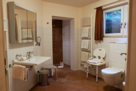 Helles Badezimmer mit Waschbecken, Toilette und Handtuchhaltern.