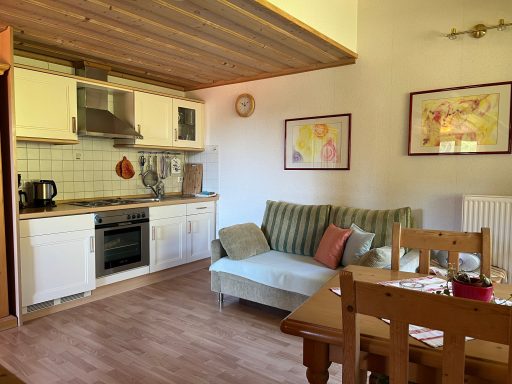 Gemütliche Küche mit Sitzbereich, Esstisch und bunten Bildern an der Wand.