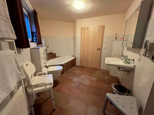Badezimmer mit Badewanne, Waschbecken, Toilette und barrierefreier Ausstattung.